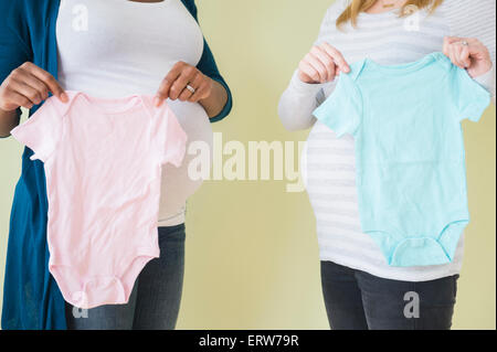 Pregnant women holding boy and girl baby clothes Stock Photo
