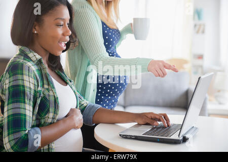 Pregnant women using laptop at table Stock Photo