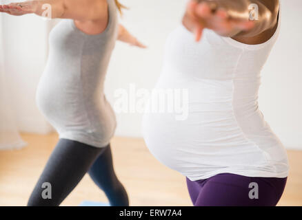 Pregnant women practicing yoga with arms outstretched Stock Photo