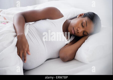 Black pregnant woman sleeping in bed Stock Photo
