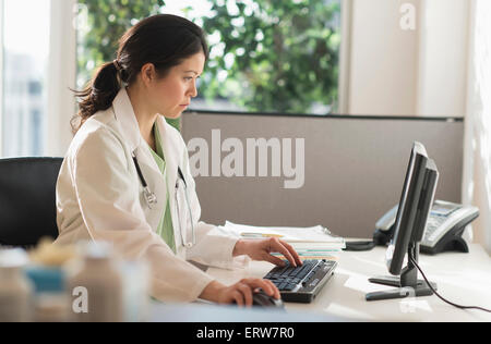 Mixed race doctor working on computer in hospital Stock Photo