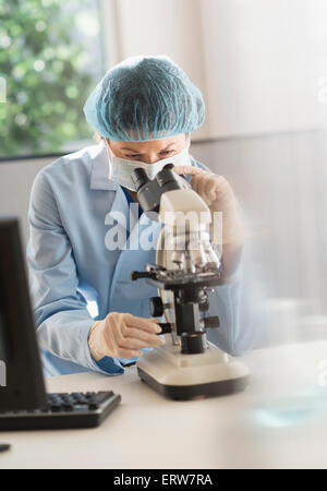Mixed race scientist using microscope in laboratory Stock Photo