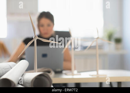 Mixed race architect with windmill models using laptop Stock Photo