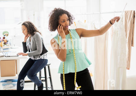 Dressmaker talking on cell phone in office Stock Photo