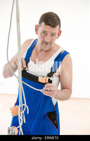 electrician in a boilersuit is working on a cable Stock Photo