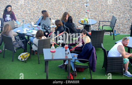 Brighton UK June 2015 - People smoking shish hookah hubble bubble pipe at The Catch bar on Brighton beach seafront Stock Photo