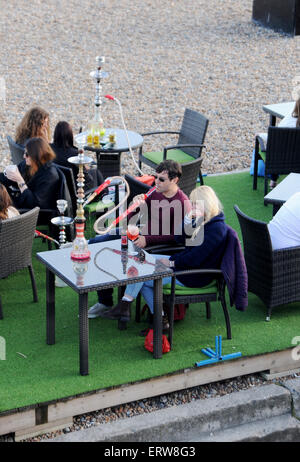 Brighton UK June 2015 - People smoking shish hookah hubble bubble pipe at The Catch bar on Brighton beach seafront Stock Photo