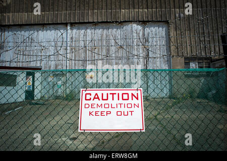 Caution demolition keep out sign on a fence of a construction site Stock Photo