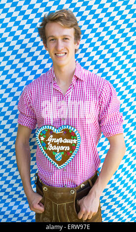 portrait of a young man in traditional bavarian costume and a gingerbread heart Stock Photo
