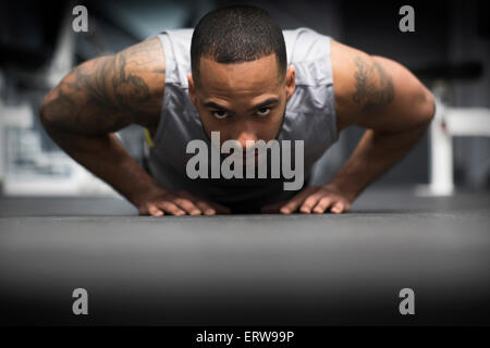 Hispanic man doing push-ups in gym Stock Photo