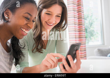 Smiling women texting on cell phone Stock Photo