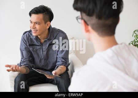 Men using digital tablet in living room Stock Photo