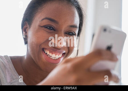 Smiling African American woman texting on cell phone Stock Photo