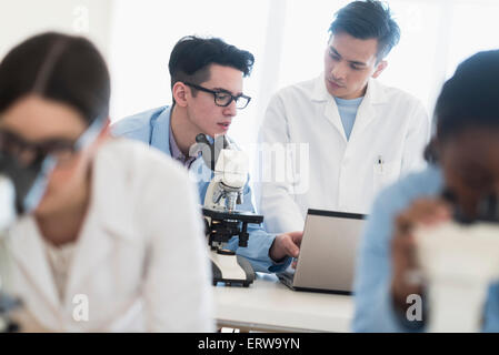 Scientists using microscopes and laptop in research laboratory Stock Photo