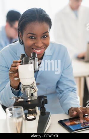 Scientist using microscope and digital tablet in research laboratory Stock Photo