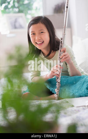 Chinese girl holding flute on bed Stock Photo