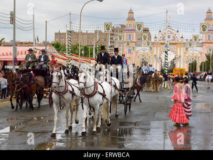 horse team pulling carriages with families on washed street at the Main Gate 2015 Seville April Fair Stock Photo