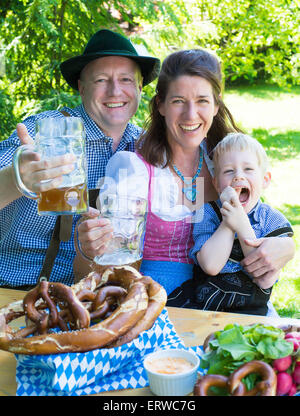 bavarian family sitting outside on a bench and smiling Stock Photo