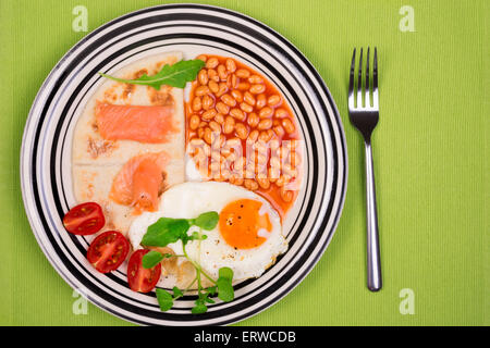 Breakfast plate with fried egg, baked beans, potato scones and smoked Scottish salmon from above Stock Photo
