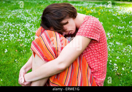 woman sitting on grass being thoughtfully Stock Photo