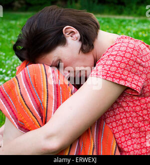 woman sitting on grass being thoughtfully Stock Photo