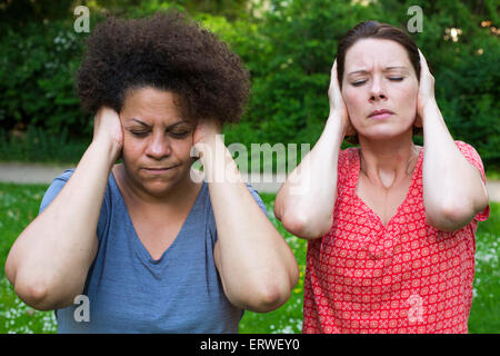 two women in park covering her ears and closing her eyes Stock Photo