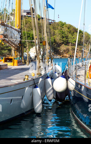 Classic yachts and fenders moored in Falmouth, Antigua with villas in the background Stock Photo