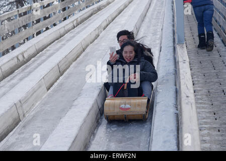 A young couple sledging on the 1884 sledge run on Terrasse Dufferin Quebec City Canada, with the man filming a selfie film Stock Photo