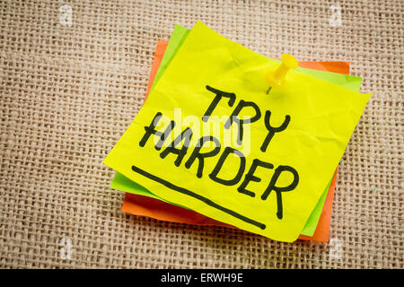 try harder - motivation words on a  yellow sticky note against burlap canvas Stock Photo