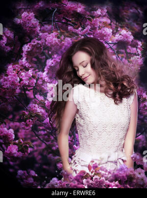 Pure Beauty. Dreamy Young Woman among Flowering Trees Stock Photo