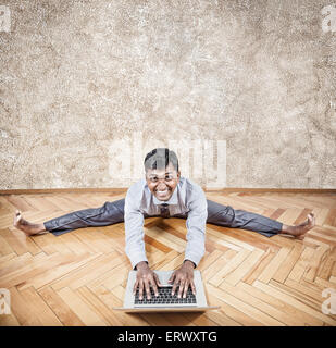 Happy Indian businessman doing yoga with laptop in the office Stock Photo