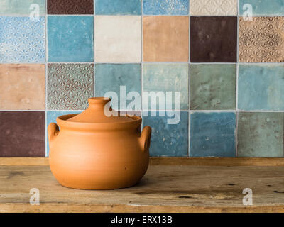 handmade ceramic pot in front of a colorful tiled wall in a countryside kitchen Stock Photo
