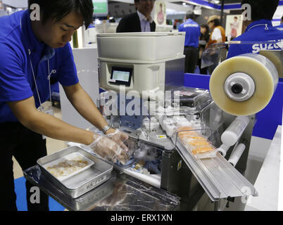 Tokyo, Japan. 9th June, 2015. A staff operates a sushi robot at the International Food Machinery and Technology Exhibition in Tokyo, Japan, June 9, 2015. The four-day exbihition kicked off in Japan on Tuesday with the participation of 681 companies. Credit:  Stringer/Xinhua/Alamy Live News Stock Photo