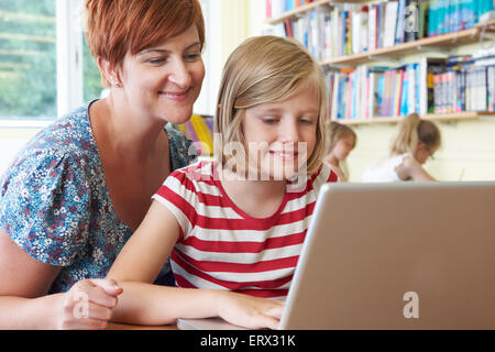 School Pupil With Teacher Using Laptop Computer In Classroom Stock Photo