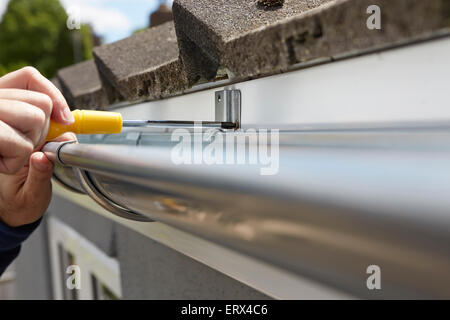 Close Up Of Man Replacing Guttering On Exterior Of House Stock Photo