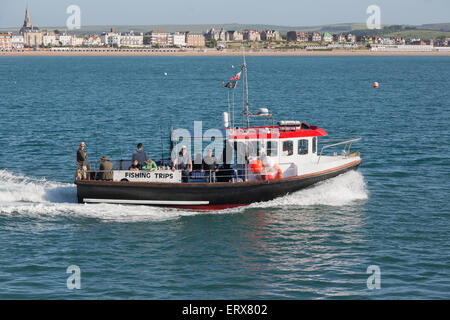 Anglers on a fishing trip leaving port to enjoy a day at sea in good weather Stock Photo