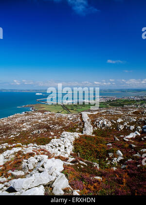 View along the ramparts of Caer y Twr Iron Age hillfort, Holyhead Mountain, Anglesey, to Holyhead harbour & breakwater, with departing Irish ferry. Stock Photo