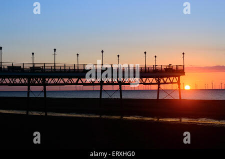 Skegness pier, at sunrise, in June. Wind farm can be seen in the distance. In Skegness, Lincolsnhire, England Stock Photo