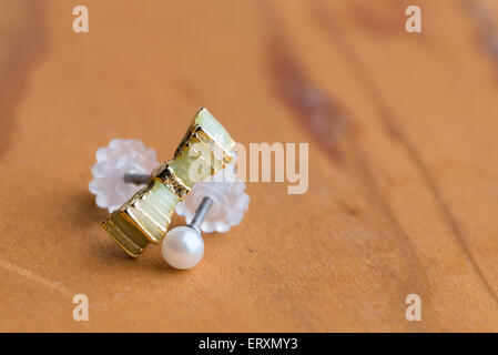 A macro shot of a green ribbon earring and white pearl earring. Stock Photo