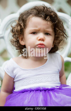 little girl sitting on chair and is pouting Stock Photo