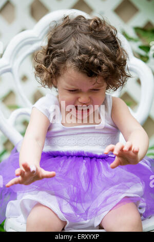 little girl in tutu sitting on chair and is crying Stock Photo