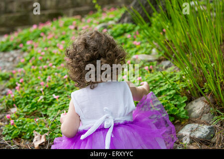 backside of little girl wearing purple tutu in garden Stock Photo
