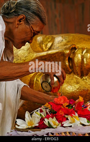 Woman worshiping statue of Lord Buddha Maha parinirvan ; Buddhist site ; Kushinagar ; Uttar Pradesh ; India Stock Photo