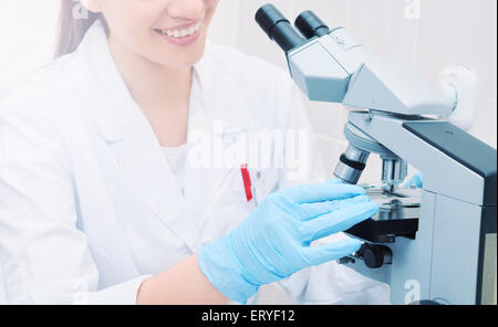 young woman medical researcher looking through microscope in laboratory, medicine concept Stock Photo