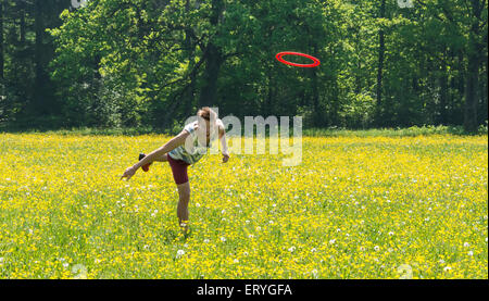 Young man throwing frisbee in meadow, Perlacher Forst, Munich, Bavaria, Germany Stock Photo