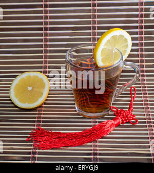 glass of tea and nearby lemon, on a rug Stock Photo