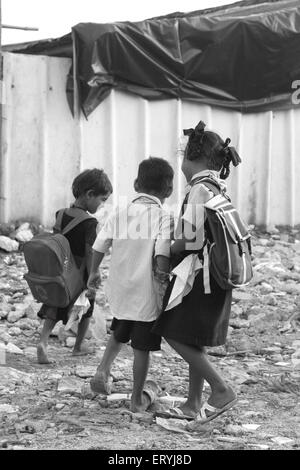 School children carrying heavy bags Malvani slum Malad Bombay Mumbai Maharashtra India Indian school going girls Stock Photo