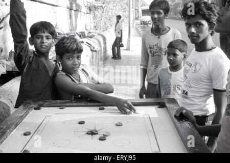 Slum children playing carom ; Bombay Mumbai ; Maharashtra ; India NO MR Stock Photo