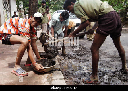 Contract labourers remove garbage and mud on the road in Bombay Mumbai ; Maharashtra ; India Stock Photo