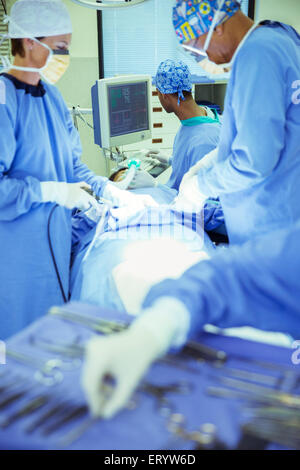 Surgeons performing surgery in operating room Stock Photo